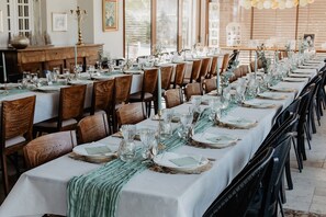 A long dining table set with chairs, glassware, and plates, indicating a formal dining area.