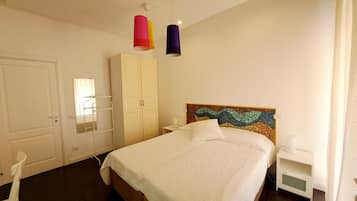 A bedroom with a bed, a wardrobe, a bedside table, and a colorful headboard.