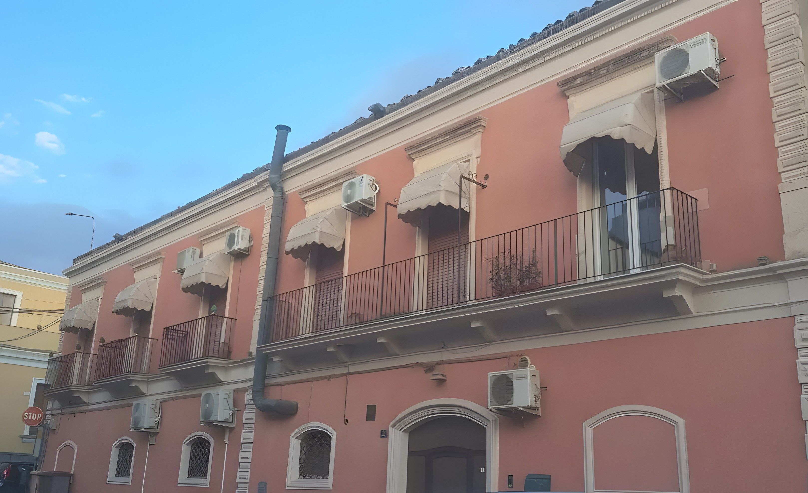 A building with multiple air conditioning units, balconies with railings, and a stop sign.