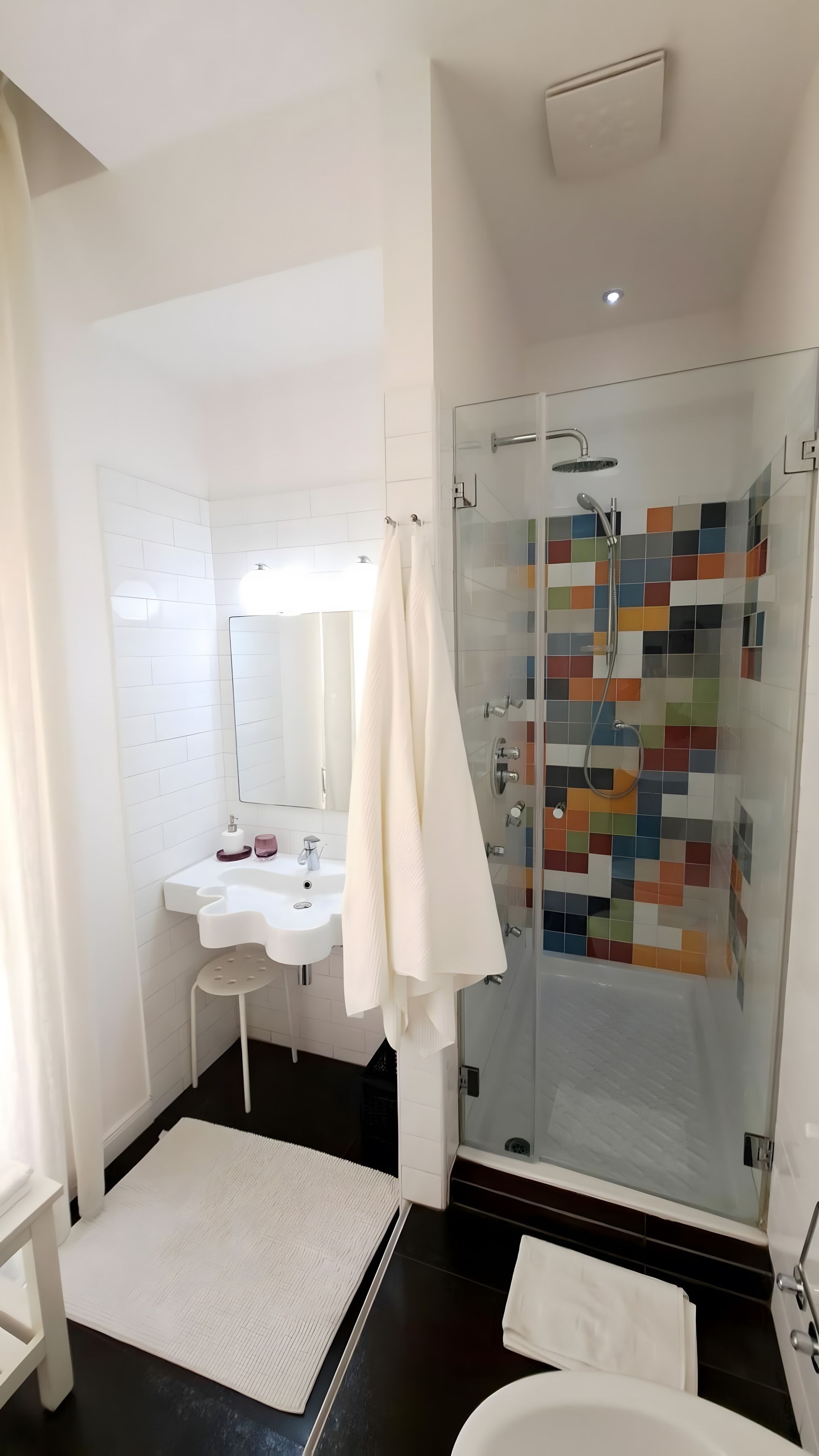 A modern bathroom with a glass-enclosed shower, a white sink, and a large mirror.