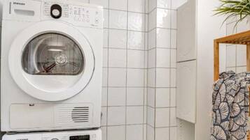 Een voorlader wasmachine in een badkamer met betegelde muren en een houten deur.
