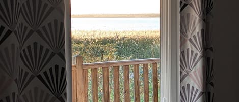 A room with a view of the beach, a wooden deck, and patterned curtains.
