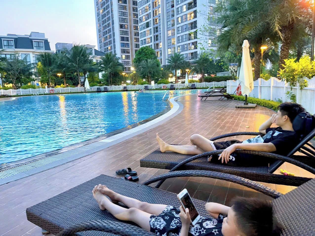 A poolside area with lounge chairs and a person using a smartphone.
