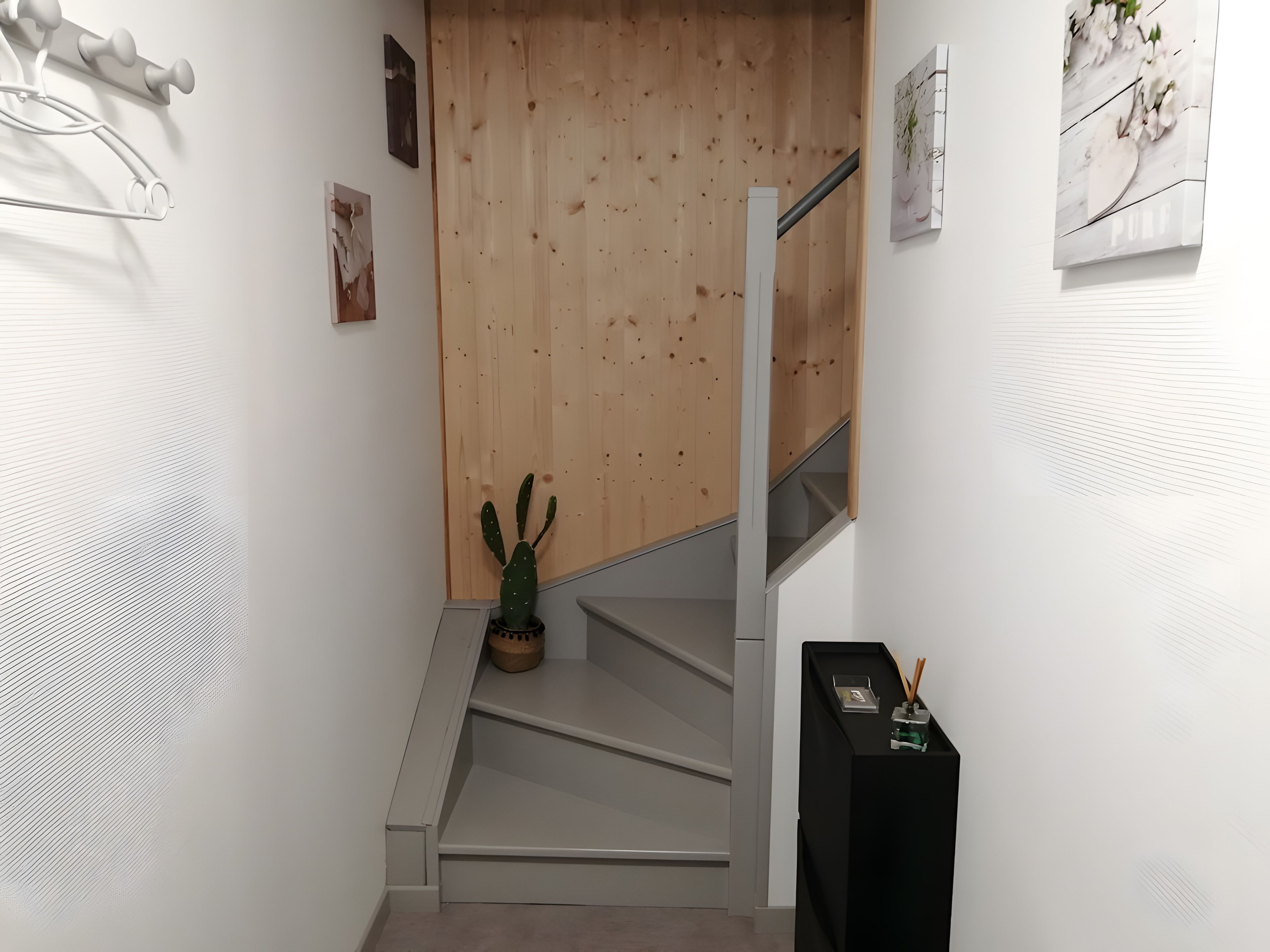 Een trap met een houten wand en een cactus op de landingsplaats.