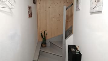 Een trap met een houten wand en een cactus op de landingsplaats.