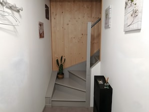 Eine Treppe mit einer Holzvertäfelung und einem Kaktus im Vorraum.