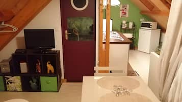 Een gezellig zolderkamer met een televisie, een klein tafeltje en een kitchenette.
