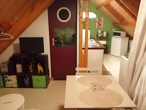 Een gezellig zolderkamer met een televisie, een klein tafeltje en een kitchenette.