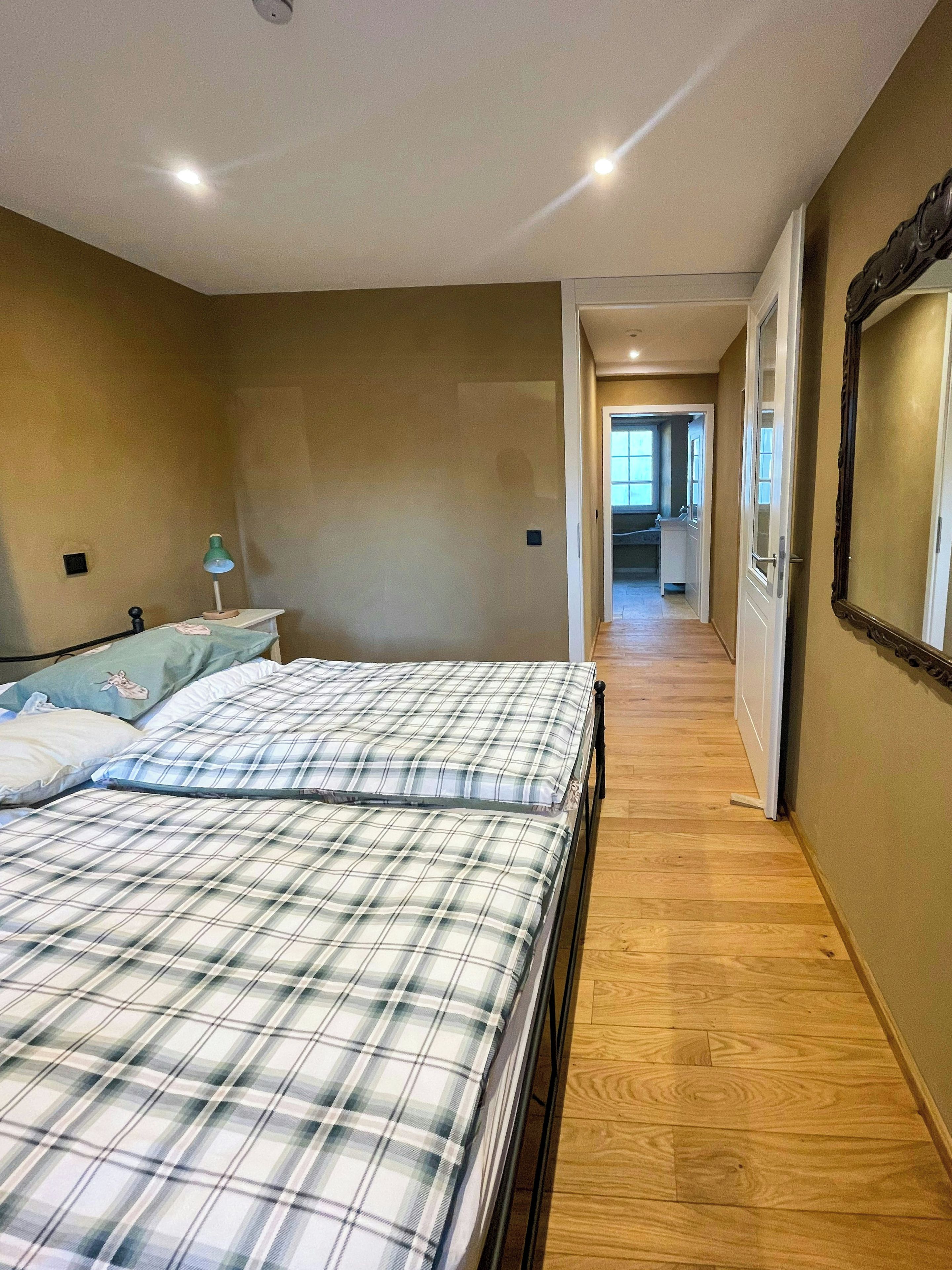 Ein Schlafzimmer mit einem Bett, einem Nachttisch, einer Lampe und Holzboden.