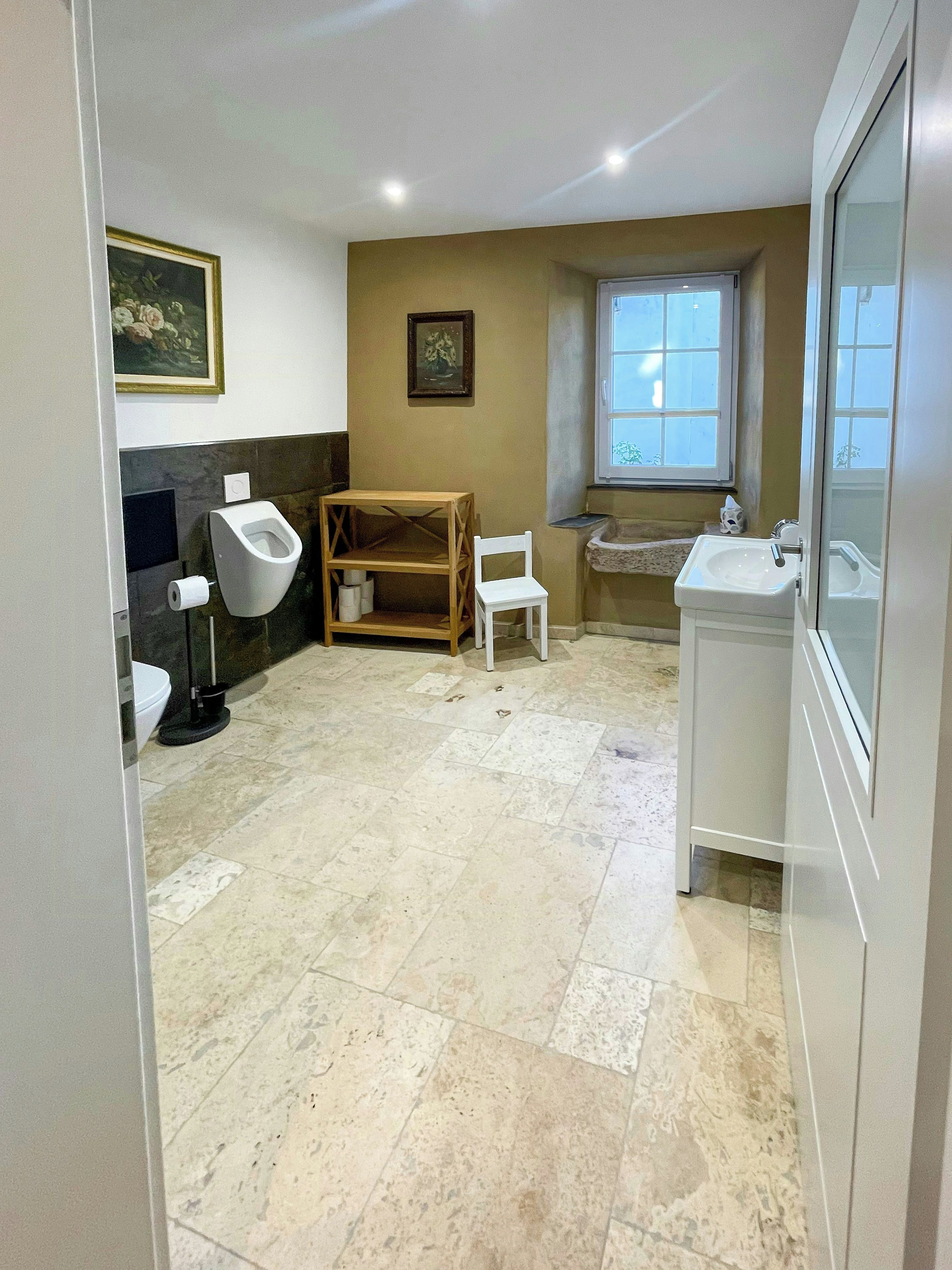 Ein Badezimmer mit Toilette, Bidet, Waschbecken und einem kleinen Holzstuhl.