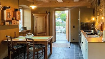 Ein Holzinterieur mit Esstisch und Stühlen, einer Küchenzeile und Blick durch einen offenen Durchgang.