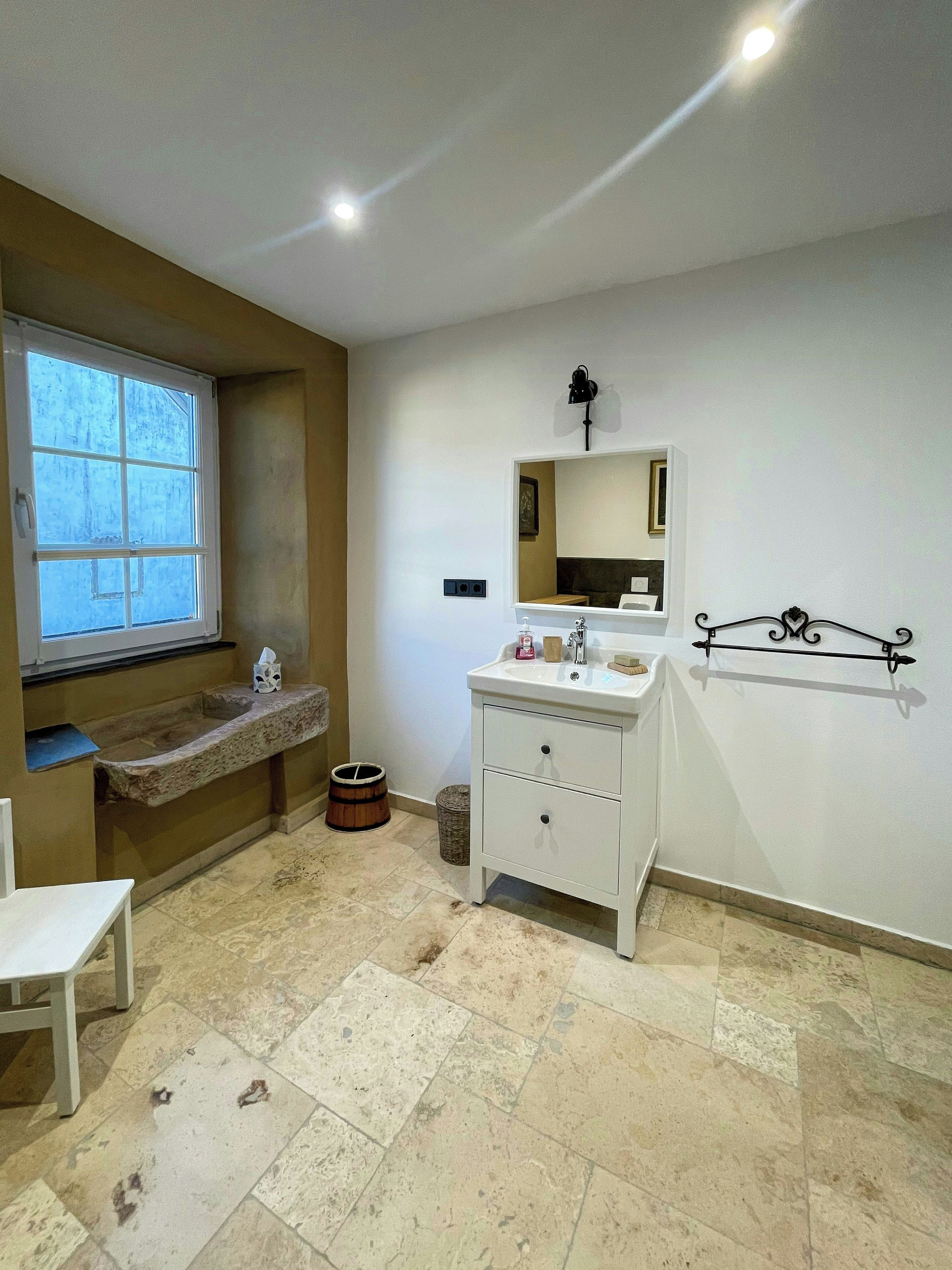 Un bagno con finestra, lavandino, specchio e water.