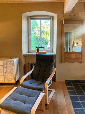 A room with a window, a chair, a small table, and a cabinet. - Historic Apartment in the Eifel Village of Ormont (Ormont)