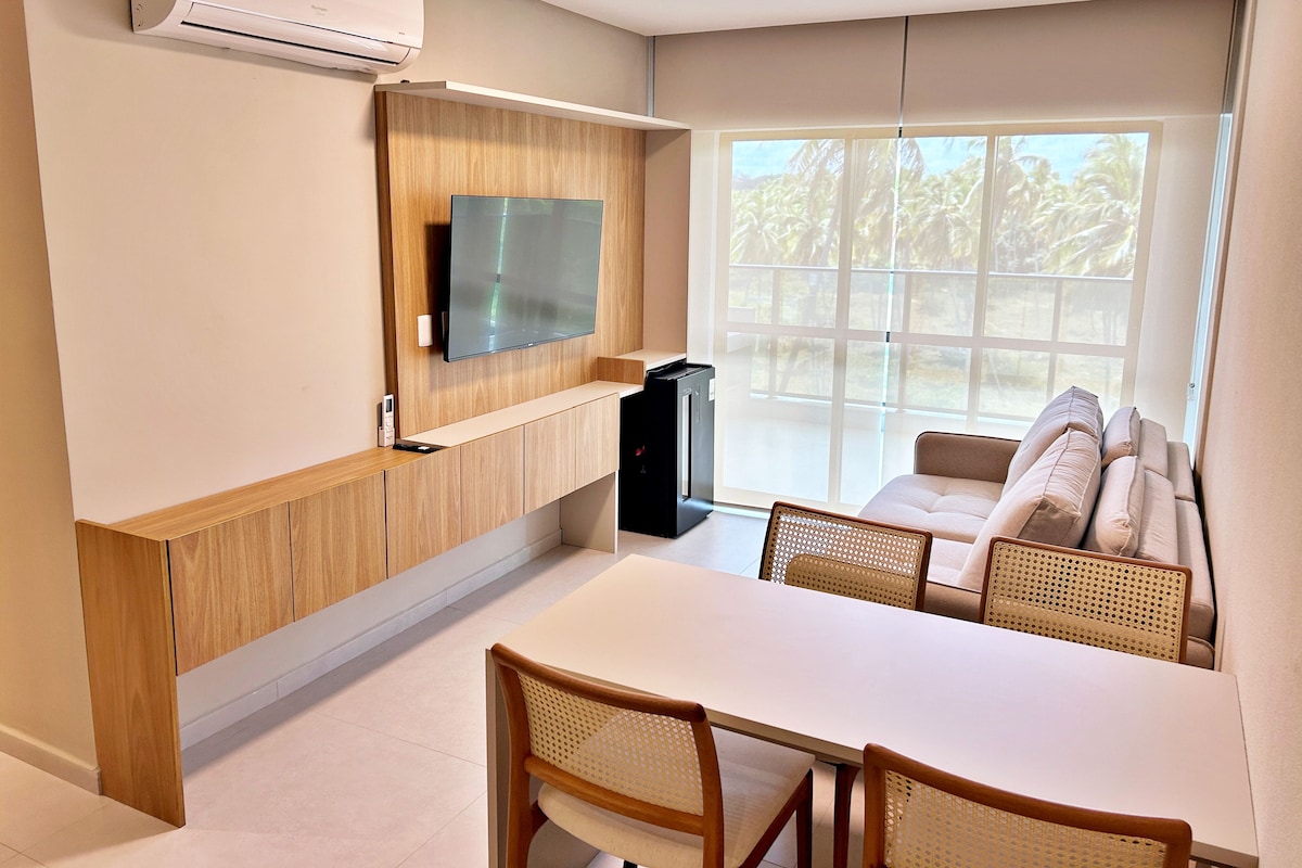 A modern living room with a flat-screen TV, a dining table, and a sofa.