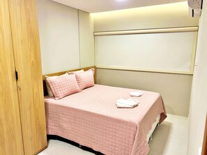 Un dormitorio con cama, almohadas, una mesita de noche y un armario.