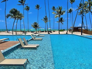 A clear blue pool with lounge chairs and palm trees, surrounded by a sandy beach and ocean view. - Vacanze - Ipioca Beach (Maceió)