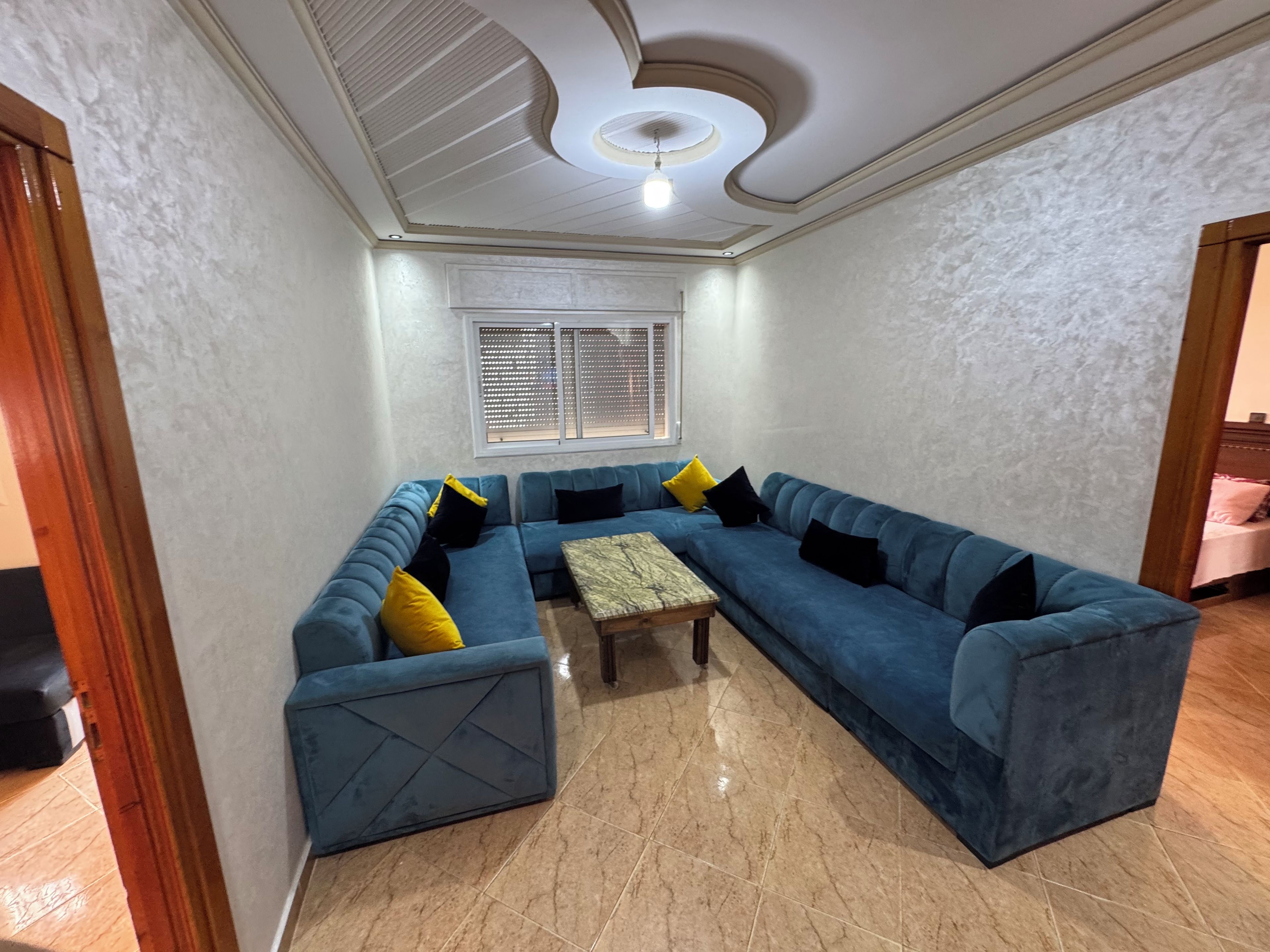 A living room with a sectional sofa, a coffee table, and a ceiling with a circular light fixture.