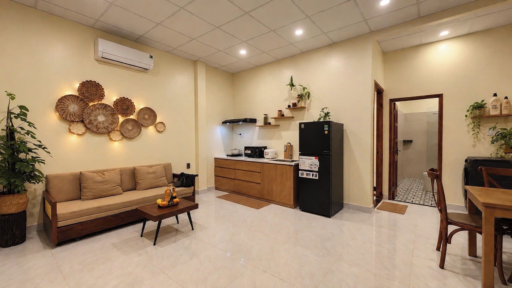 Un espacio habitable compacto con sofá, mesa de centro, kitchenette y zona de comedor.