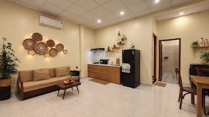 Un espacio habitable compacto con sofá, mesa de centro, kitchenette y zona de comedor.
