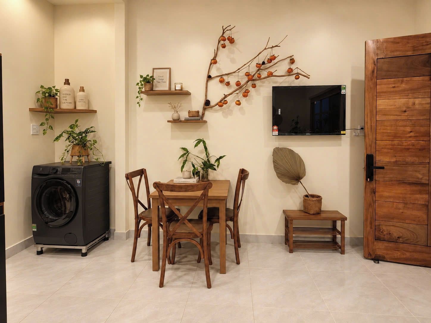 Un espacio habitable funcional con una mesa de comedor, sillas, lavadora, televisor y decoración mural.