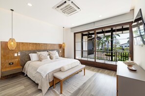 Una camera da letto moderna con un letto grande, una testiera in legno e un balcone che si affaccia su palme.