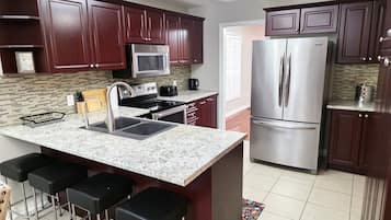 A kitchen with dark wood cabinets, a stainless steel refrigerator, a microwave, and a granite countertop.