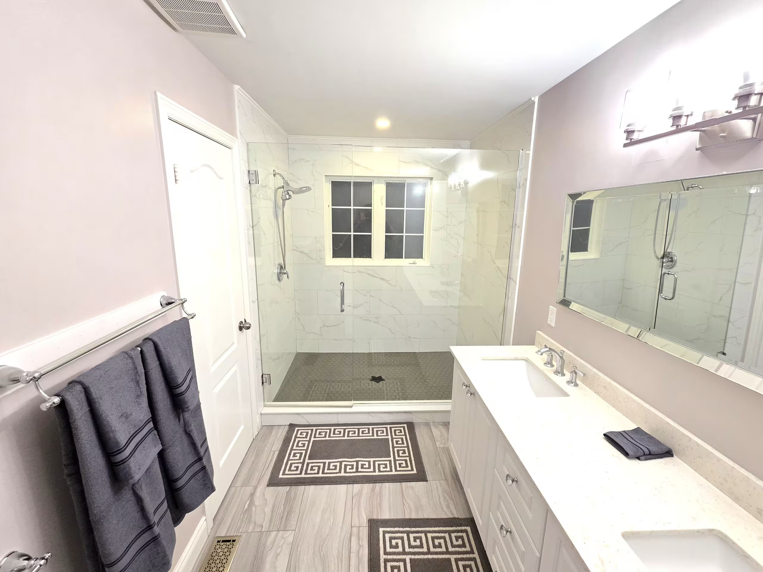 A modern bathroom with a walk-in shower, a large mirror, and a vanity with a sink.