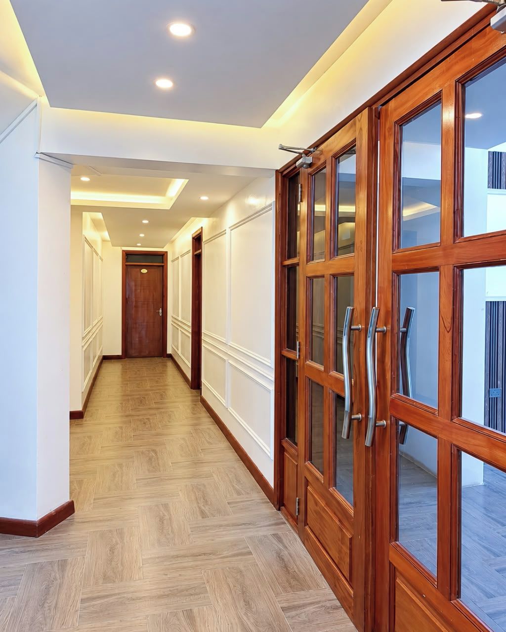 A hallway with wooden doors and a herringbone floor pattern.