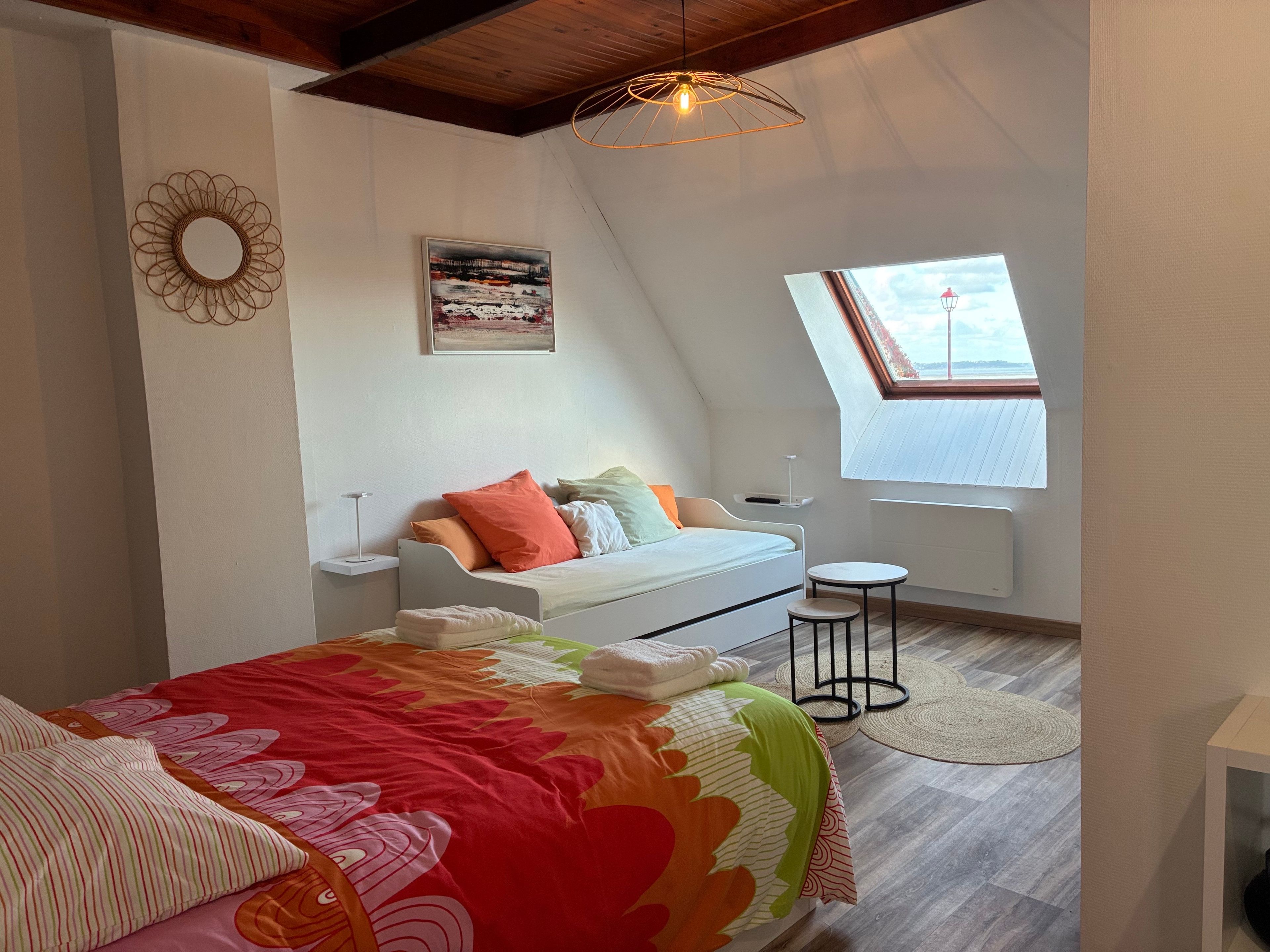 Une chambre à coucher comprenant un lit, une table de chevet, une fenêtre et un luminaire au plafond.