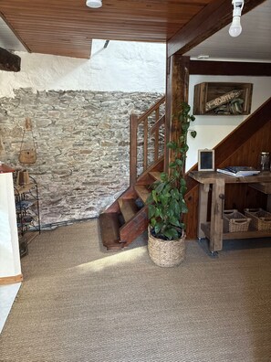 A staircase with a wooden railing leading to a loft area, a stone wall, and a plant in a basket.