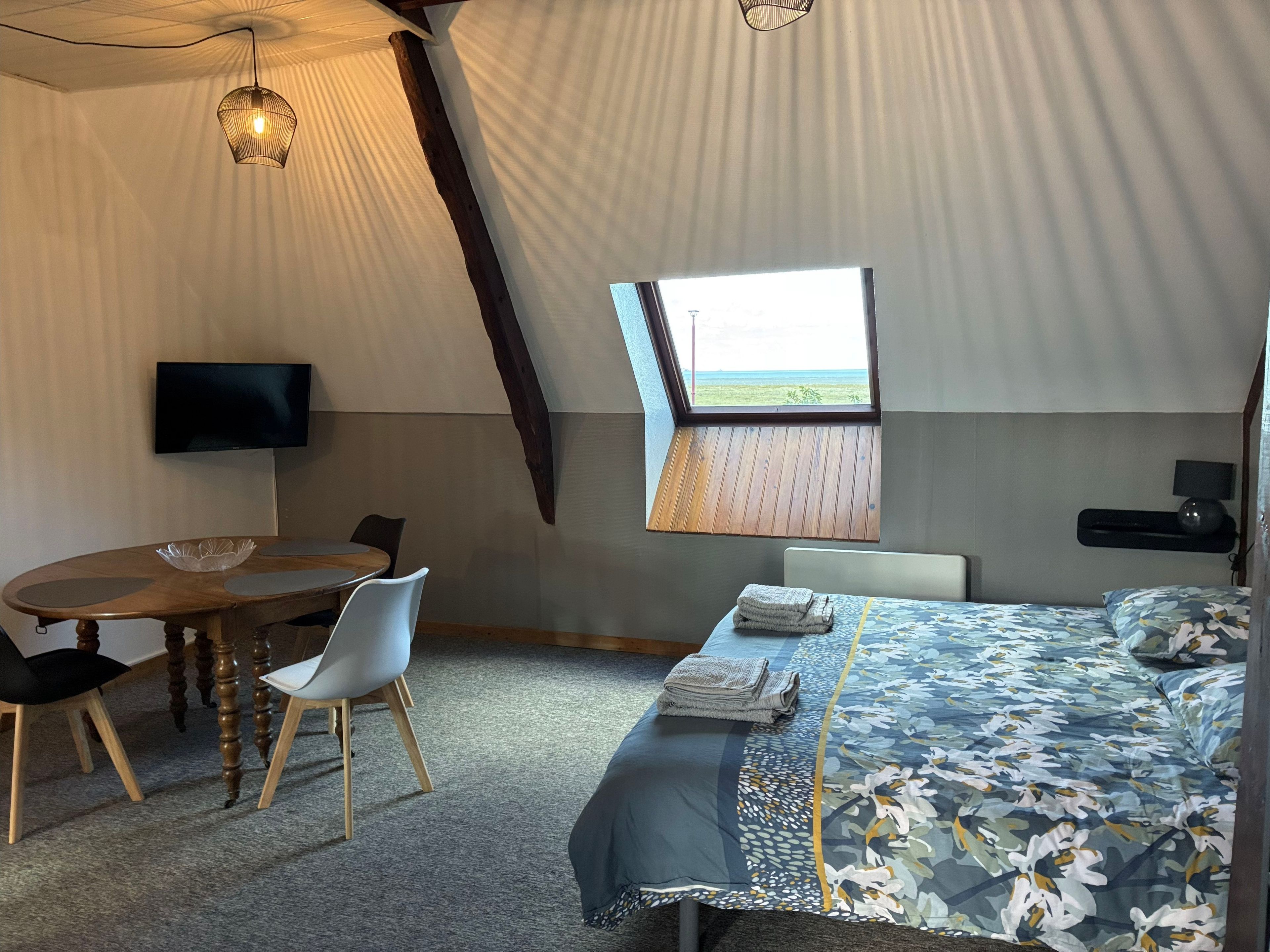 Une chambre d’hébergement sous tente comprenant un lit, une table avec des chaises, un téléviseur et une fenêtre donnant sur un paysage agréable.