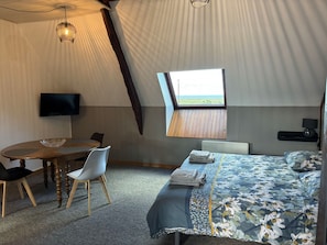 Ein Zeltunterstand mit einem Bett, einem Tisch mit Stühlen, einem Fernseher und einem Fenster mit Blick.