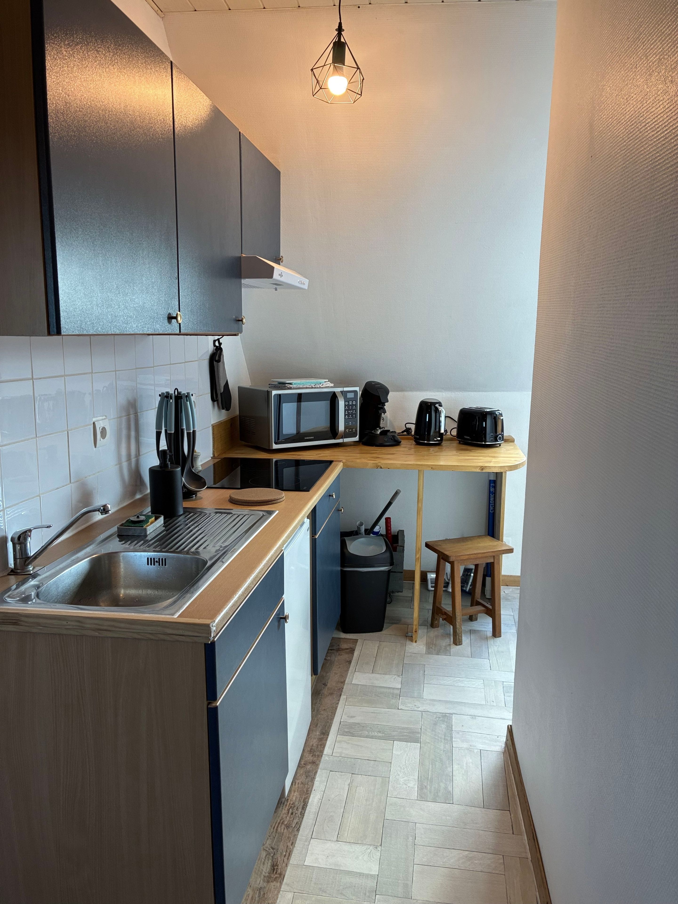 Eine kleine Küche mit Mikrowelle, Kaffeemaschine, Toaster und einem kleinen Hocker.