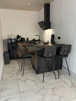A modern kitchen with a central island, bar stools, a built-in oven, and a range hood.