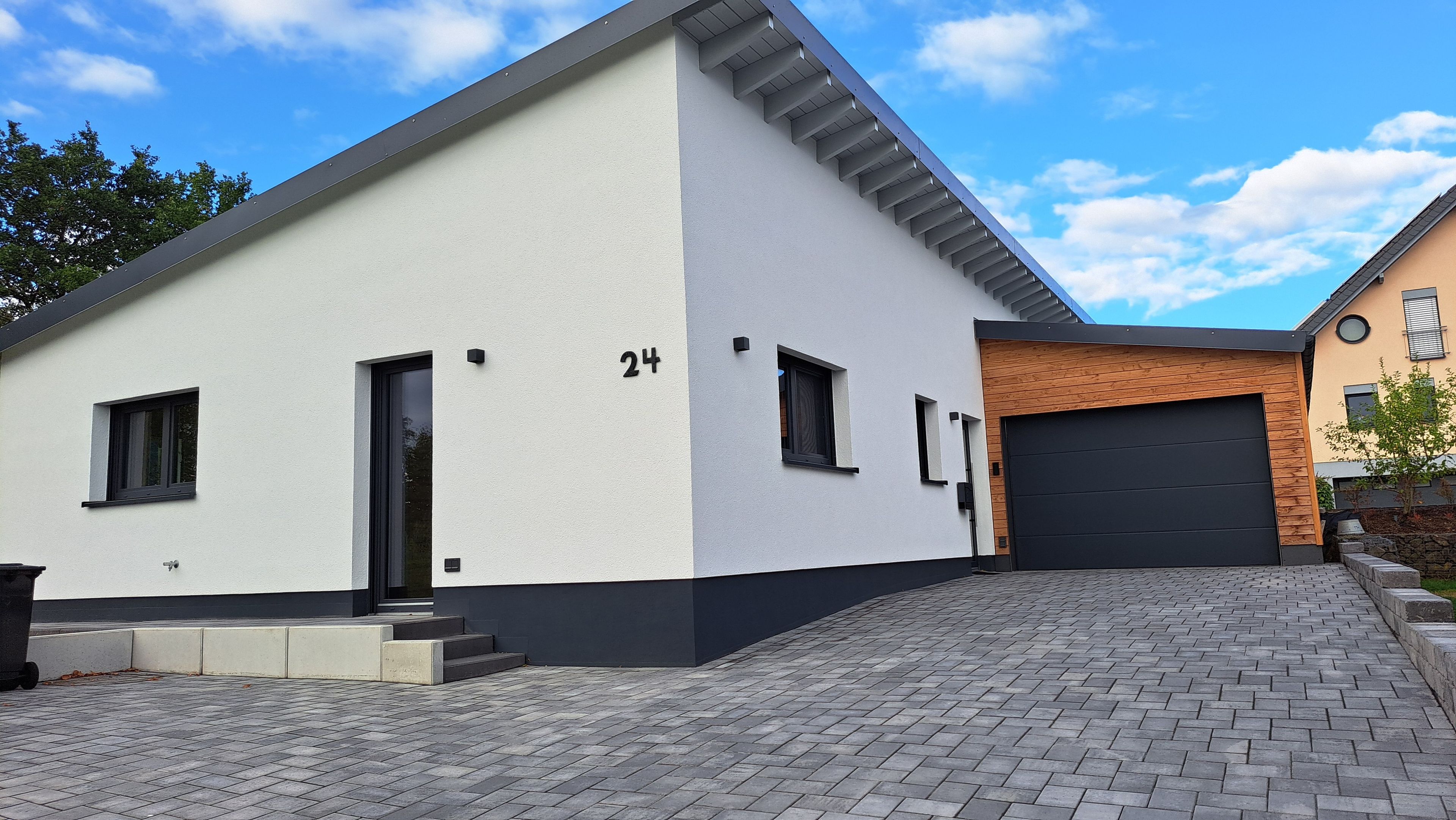 Ein modernes, zweistöckiges Haus mit Garage, Auffahrt und der Hausnummer 24 an der Fassade.