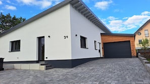 Una casa moderna de dos pisos amb garatge, una entrada i el número 24 a la façana.