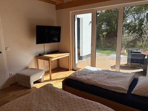 A room with a bed, a desk, a television, and a sliding glass door leading to an outdoor area with a patio. - Holiday Home 'Ferienhaus Thomes' in Hunsrück (Külz (Hunsrück))