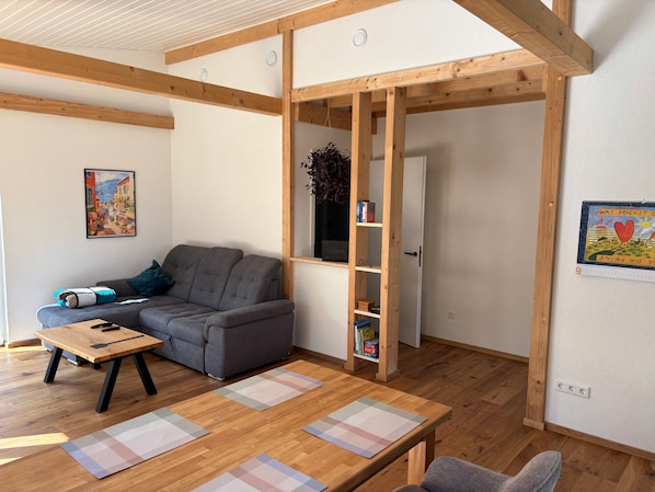 A living room with a sofa, a wooden table, and a bookshelf. - Holiday Home 'Ferienhaus Thomes' in Hunsrück (Külz (Hunsrück))