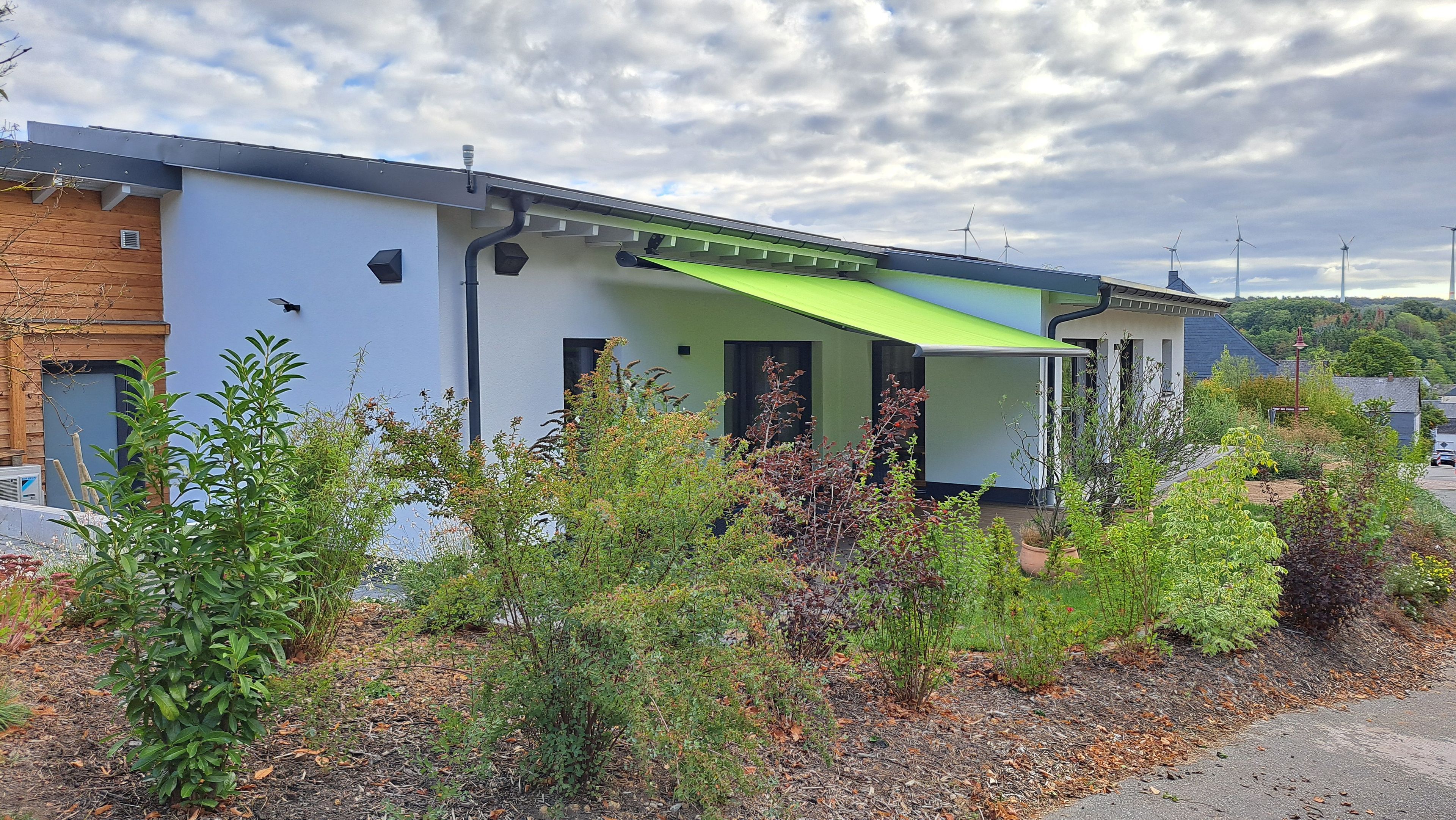 A modern building with a flat roof, a green awning, and a brick section on the left.