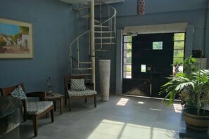 A room with a spiral staircase, a large window, and a potted plant. - Hotel Posada Urbana (Puerto Vallarta)