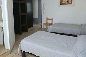 A room with two beds, a chair, a door, and a wall-mounted light switch. - Hotel Posada Urbana (Puerto Vallarta)