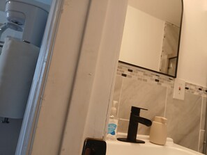 A bathroom with a white sink, a black faucet, a mirror, and a tiled backsplash. - New Listing (Tampa)