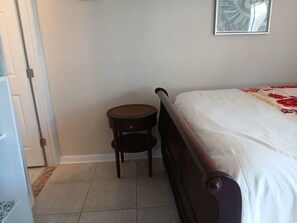 A bedroom with a bed, a small wooden nightstand, and a door. - New Listing (Tampa)