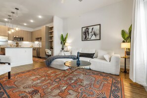A modern living room with a sofa, a coffee table, and a patterned rug. - Sophisticated 1BR w/ Stylish Escape SHI-2207 (Austin)