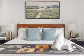 Ein ordentlich bezogenes Bett mit einer gemusterten Tagesdecke, zwei Kissen und einem zusammengerollten Handtuch.