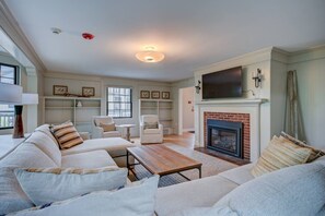 A spacious living room with a fireplace, comfortable seating, and a flat-screen TV mounted above it. - Upscale 5BR | Walk to Dining + Downtown (Conway)