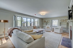 A spacious living room with a large sofa, two armchairs, a coffee table, and a fireplace. - Upscale 5BR | Walk to Dining + Downtown (Conway)