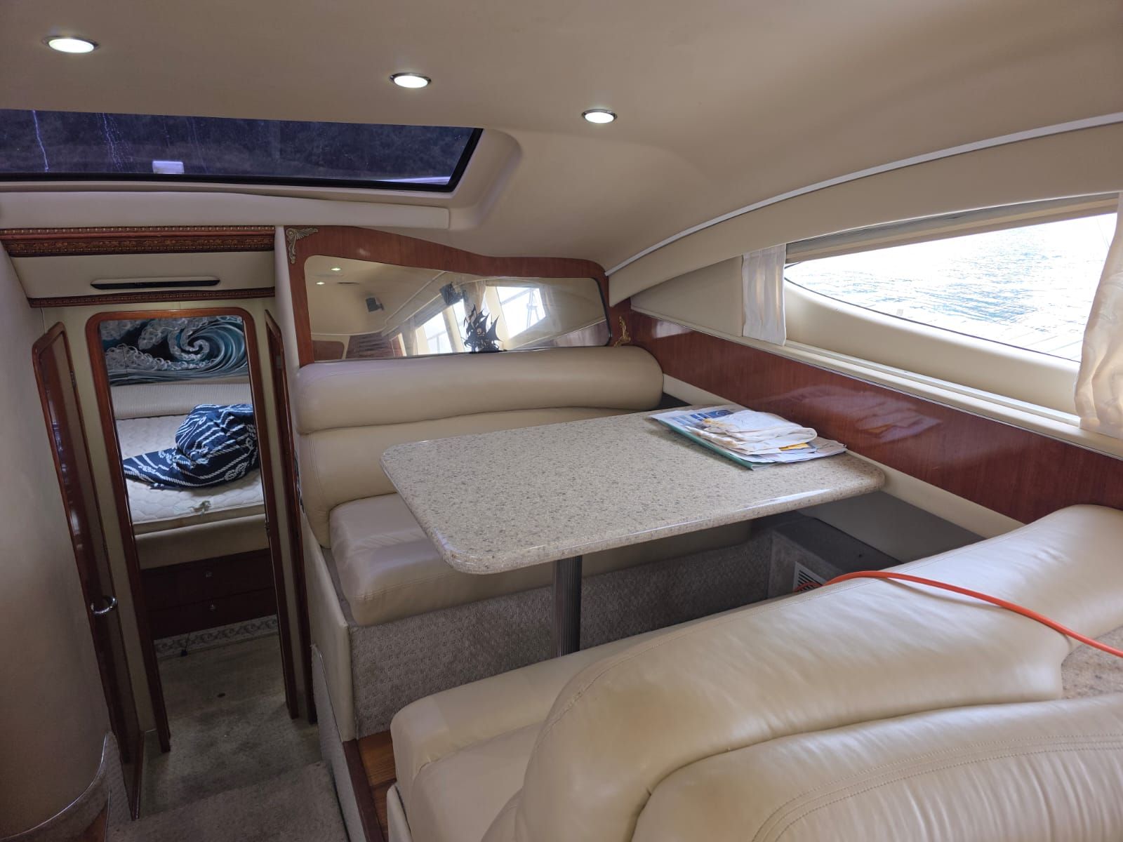 Un interior reducido con una cama litera, una pequeña mesa con papeles y un ventanal con cortinas.