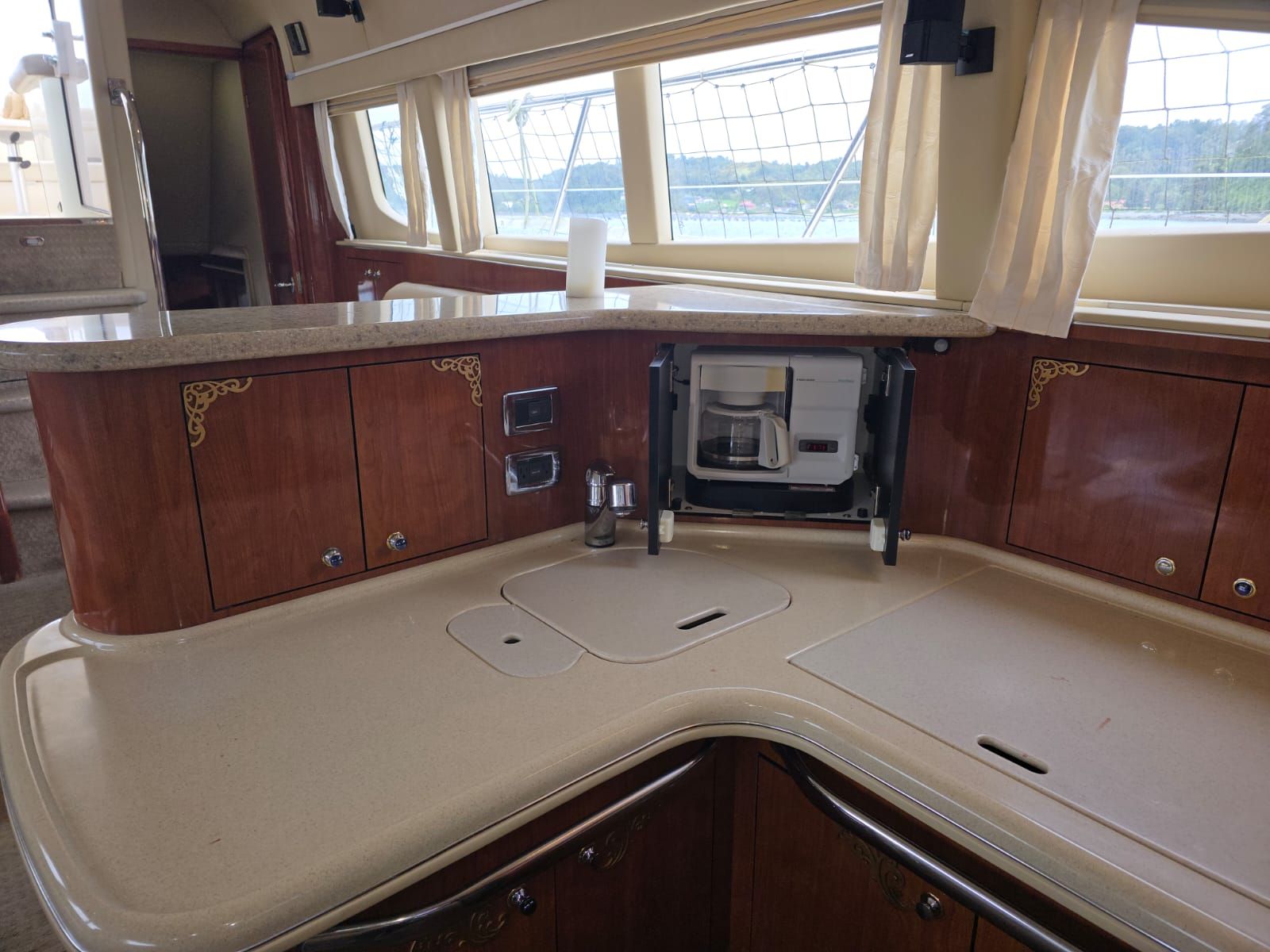 A compact kitchen with a built-in coffee maker, wooden cabinets, and a window with a view of the outdoors.