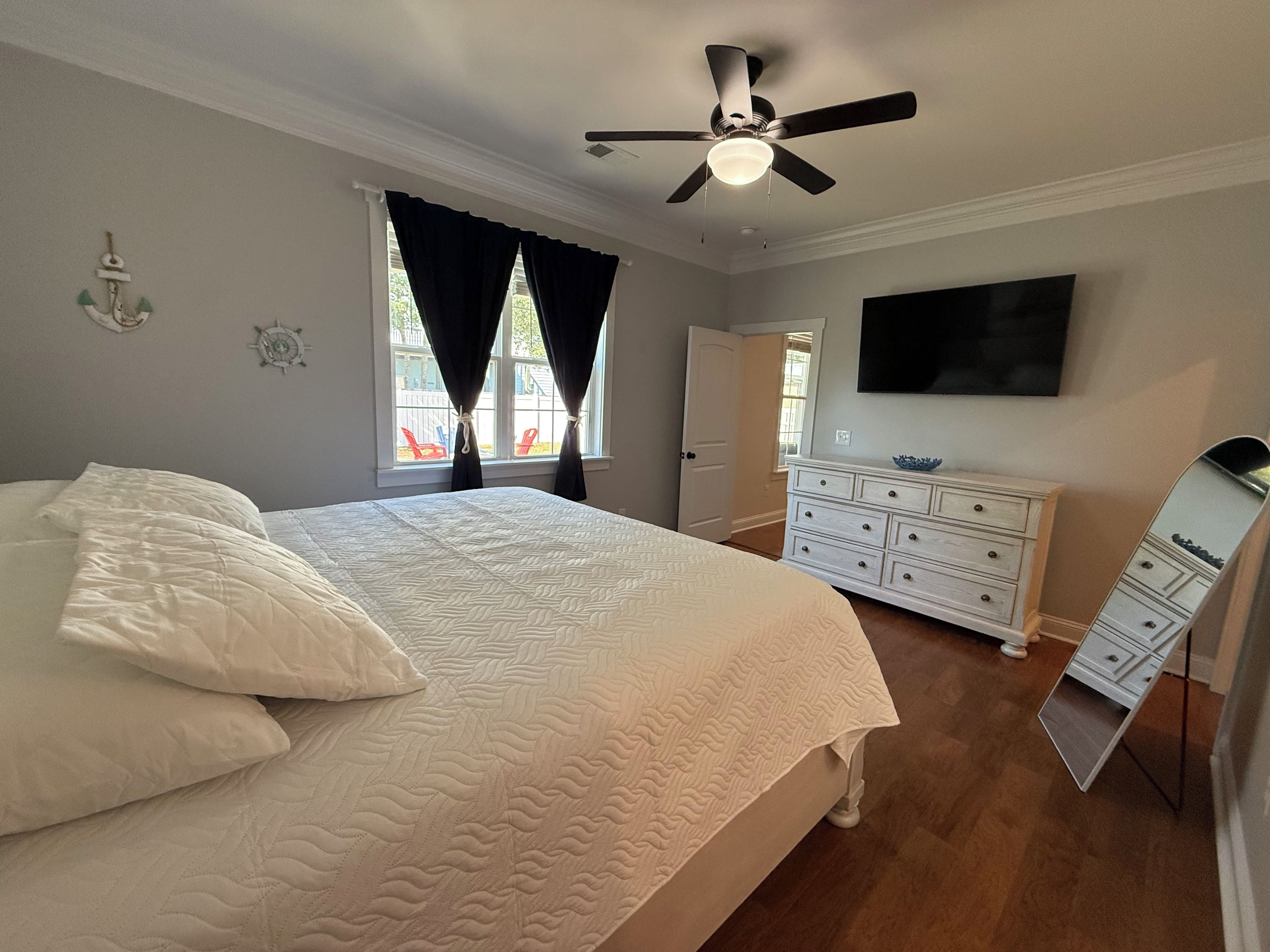 A bedroom with a bed, dresser, and ceiling fan.